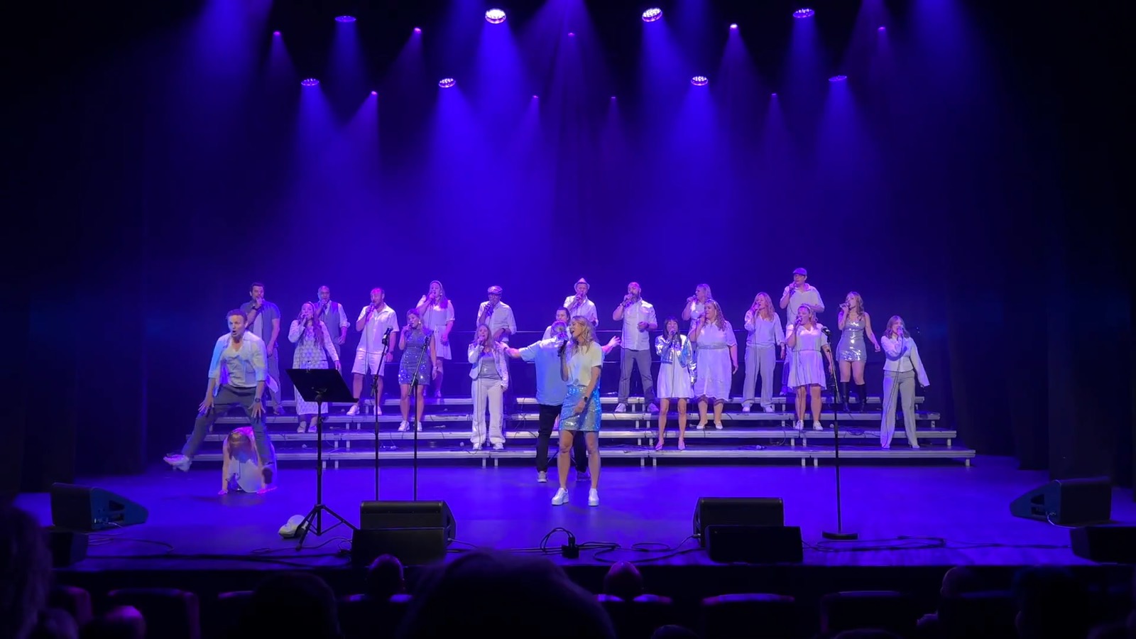 The Real Choir på scenen i blått scenelys